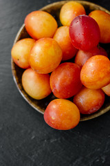 Top view of ripe wild plum fruits over black stone background.