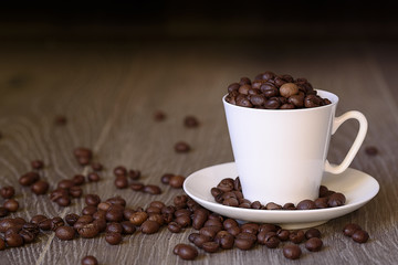 Coffee concept: fried coffee beans in porcelain white coffee cup