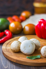 White champignon mushrooms on wooden kitchen board.