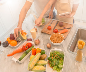 happy young couple cooking together in the kitchen at home. looking at tablet pc.