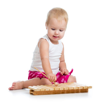 Little girl with excitement playing on xylophone isolated on white.