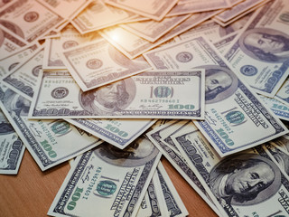 The money american hundred dollar bills put on wooden desk,blurry light background.