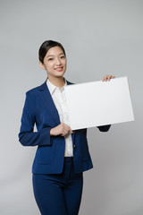 asian woman holding white blank cardboard, over gray background.