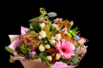 Bouquet of different flowers, roses, carnations, gerberas, sunflowers, irises, on a black background.
