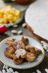 Roasted mushrooms on white ceramic plate on kitchen table.