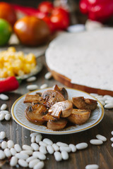 Roasted mushrooms on white ceramic plate on kitchen table.