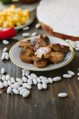 Roasted mushrooms on white ceramic plate on kitchen table.