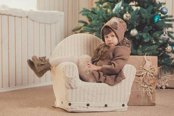 Young brunette dolly lady girl stylish dressed cozy warm winter gray jacket with fur posing sitting standing in studio close to Christmas New Year tree and presents. - obrazy, fototapety, plakaty