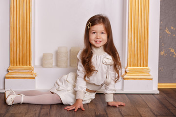 Young brunette dolly lady girl stylish dressed in white skirt midi petticoat and waist blouse smiling posing in studio close to chimney place grate with pout lips and pink cheeks.