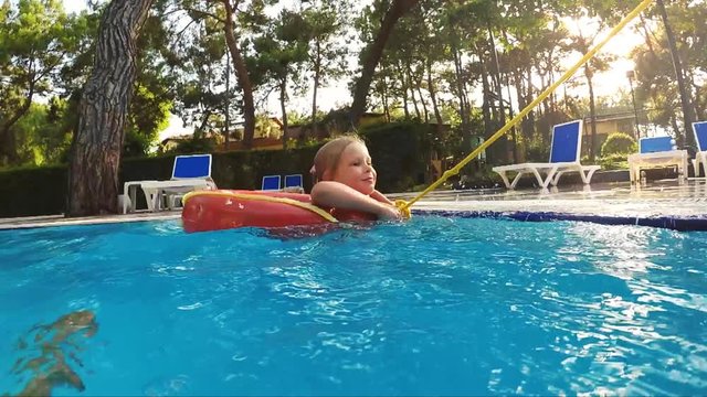 Slow motion of little girl swimming in lifebuoy in the pool. Holidays and fun concept. 