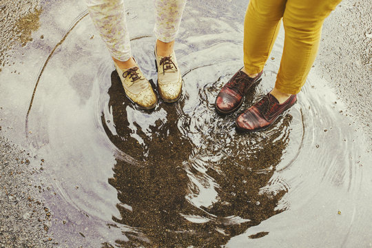 Two girls standing in a puddle of rain
