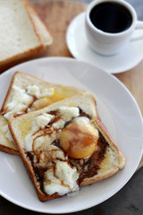 Fresh delicious breakfast with soft boiled eggs on the toasted bread with black pepper and soy sauce isolated with a cup of coffee on the wooden table