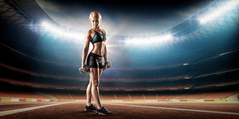 Fototapeta na wymiar beautiful sporty woman doing work out with dumbbells on stadium