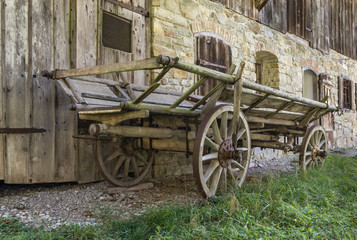 Fototapeta na wymiar Historic wooden horse driven cart in front of an old farmhouse