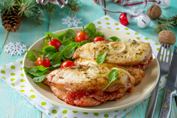 Baked chicken meat stuffed with tomatoes and cheese on a festive Christmas table.