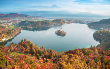 Mystical landscape with the island on Lake Bled in the morning fog in pastel colors in autumn. Scene from Osojnica viewing platform. Slovenia, Europe. Attractions. Tourist places of pilgrimage. 