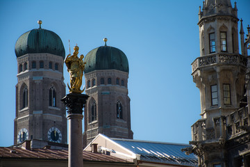 Fototapeta na wymiar Golden sculpture of St. Mary with the Church of Our Lady. View from Marienplatz in Munich, Germany