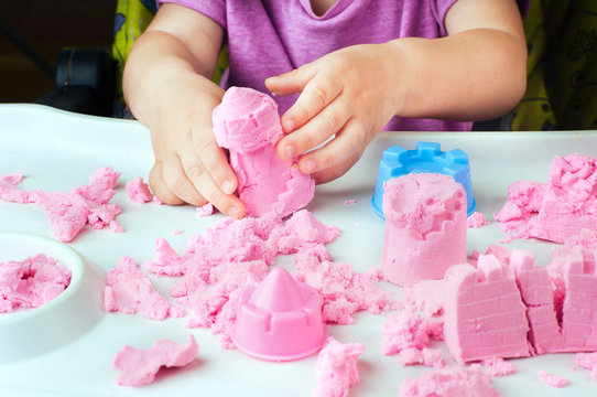Childs hands building castle from kinetic sand on the table