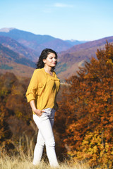Naklejka premium Beautiful young brunette enjoys a sunny day of autumn in nature