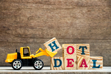 Obraz premium Toy plastic bulldozer hold letter block H to complete wording hot deal on wood background
