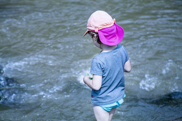 Little girl having fun by mountain  river at summer (Holiday, rest, happy childhood, games, nature concept)