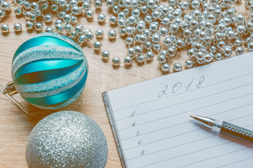 to do list on 2018 new year. notebook and black pan on table surrounding silver garland and couple...