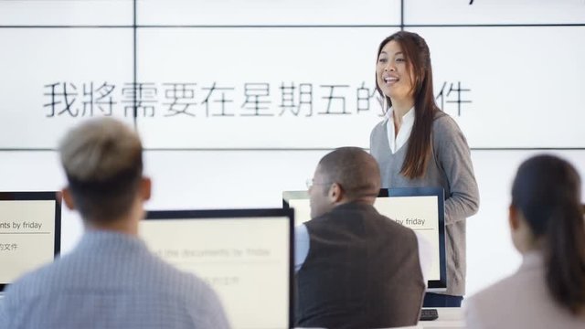  Adult students in language class with video screen showing Asian characters