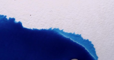 Blue ink absorbing into white paper background