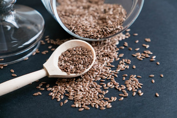 Flax seeds in spoons over dark background. Natural light. Selective focus. Close up on a black background. Top view, flat lay. copy space