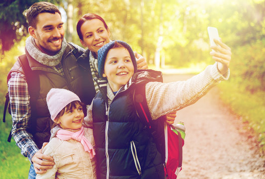 family with backpacks taking selfie by smartphone