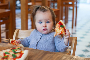 little caucasian baby girl eating pizza, fast food, unhealthy concept
