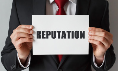 Obraz premium Businessman holding a card with text REPUTATION