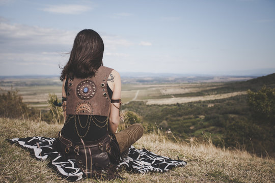 Back view of the Boho girl on a hill looking far in the distance