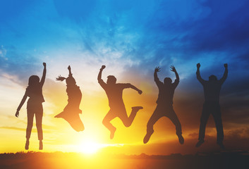 Silhouette of happiness teamwork jumping as a business successful, achieve business goal. Sunset...