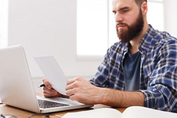Young concentrated businessman read documents in modern white office