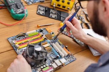 Repairman soldering computer circuit in workshop