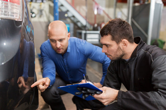 auto mechanic and customer looking at car
