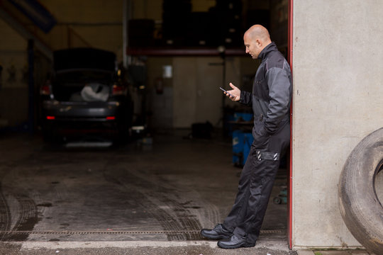 auto mechanic with smartphone at car service - Powered by Adobe