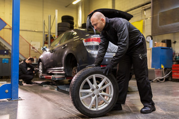 Fototapeta na wymiar auto mechanic changing car tire at workshop