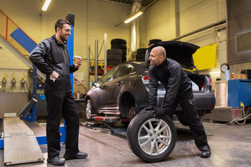 auto mechanics changing car tires at workshop - Powered by Adobe