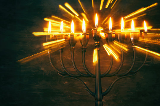 Low key image of jewish holiday Hanukkah background with menorah (traditional candelabra) and burning candles