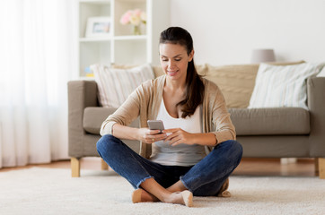 happy woman texting message on smartphone at home