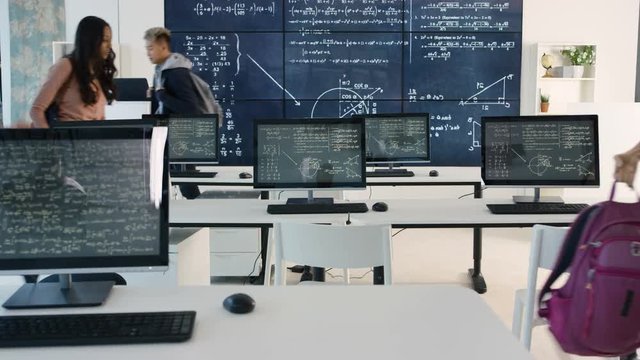  Adult student group arriving for class, math formulas on blackboard