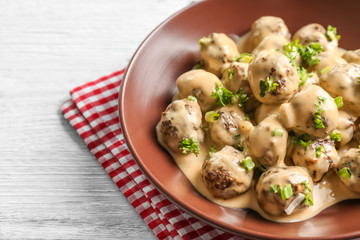 Bowl with delicious meatballs in sauce on table