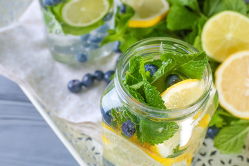 Tray with glassware of infused fruit water on wooden table, closeup
