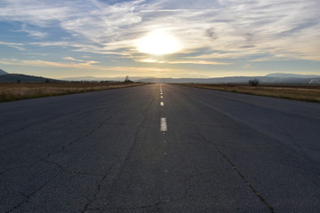 Reaching the horizon wide straight asphalt road, former airplane strip before sunset