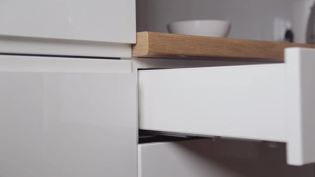 The man takes the cutlery from the pull-out kitchen box with the push system