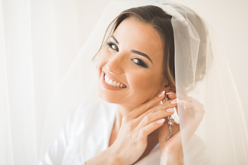 Gorgeous bride in robe posing and preparing for the wedding ceremony face in a room