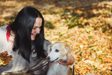  Woman embracing a cute dog in beauty in autumn scenery,shallow depth of field