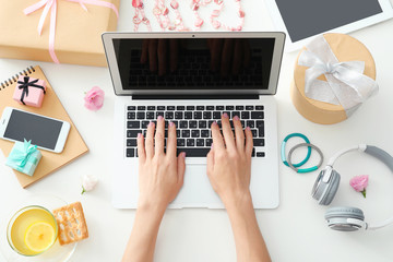 Hands of beauty blogger with laptop and different stuff on table